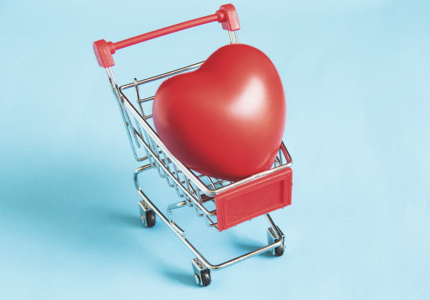 大的心形礼物在购物车孤立在蓝色柔和的背景图片下载