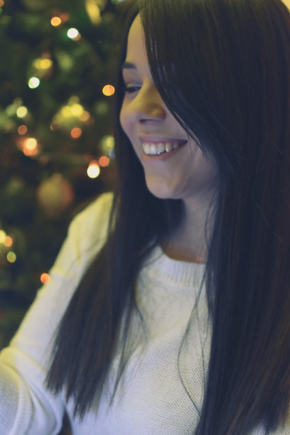 一位年轻女子坐在圣诞树旁图片下载