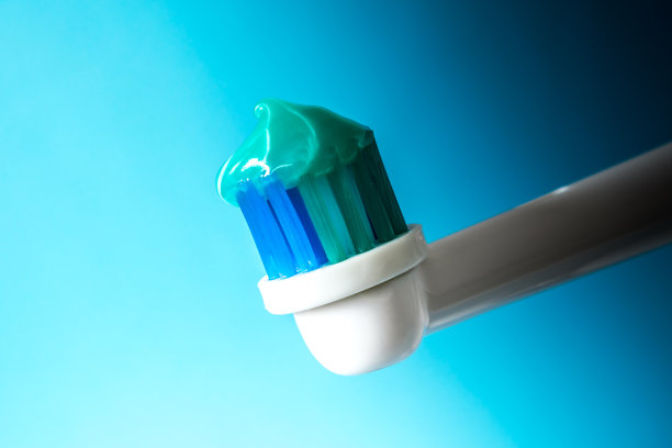 电动牙刷与绿色的薄荷味牙膏靠近在一个蓝色的背景图片下载