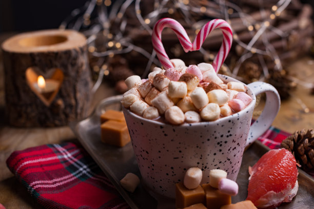 可可和棉花糖放在一个白色的杯子里，不同的圣诞糖果和糖果。照片在黑暗的风格和自由的文字空间。蜡烛和节日装饰品。图片下载