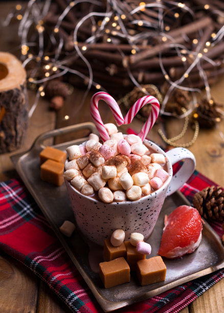 可可和棉花糖放在一个白色的杯子里，不同的圣诞糖果和糖果。照片在黑暗的风格和自由的文字空间。蜡烛和节日装饰品。明信片和问候。图片下载