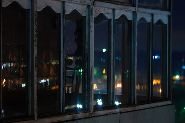 长曝光城市夜景照片。有窗户的阳台让夜晚城市的灯光透进来。图片下载