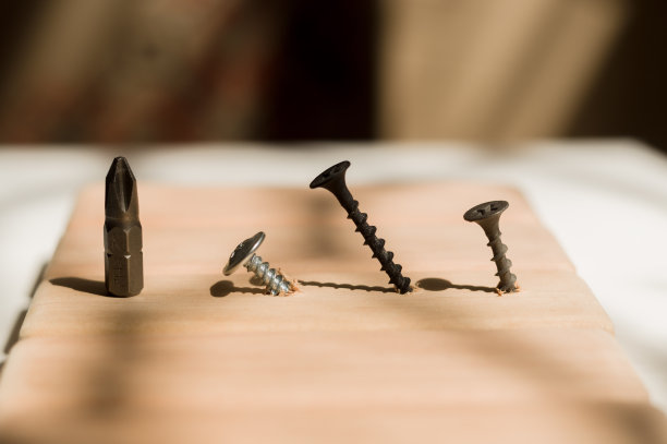 学习用螺丝刀工作。教授如何使用工具。概念上的照片。螺丝起子和三个螺丝，一个银色，两个黑色。图片下载