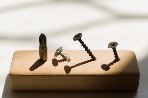 学习用螺丝刀工作。教授如何使用工具。概念上的照片。螺丝起子和三个螺丝，一个银色，两个黑色。图片下载