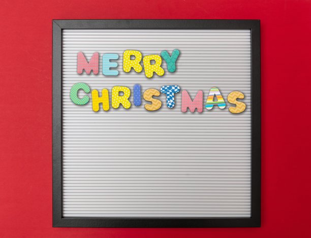 板与黑色框架，文字圣诞快乐在彩色字母，红色墙背景，复制空间图片下载