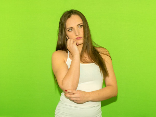 一个长头发的讨厌女孩的肖像。孤立在绿色背景上。图片下载