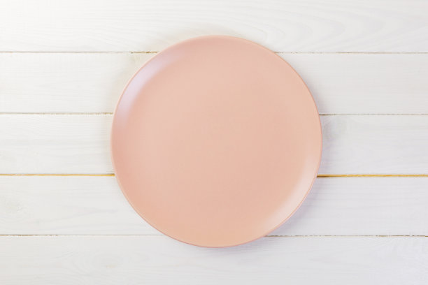白色木质背景上的晚餐用的空玫瑰磨砂盘子图片下载