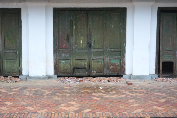 老挝琅勃拉邦古老白色石膏墙上的破旧木门图片下载