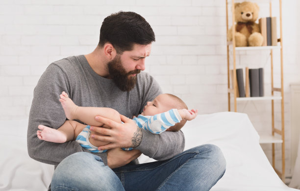 刚出生的婴儿在父亲的手中哭泣在床上图片下载