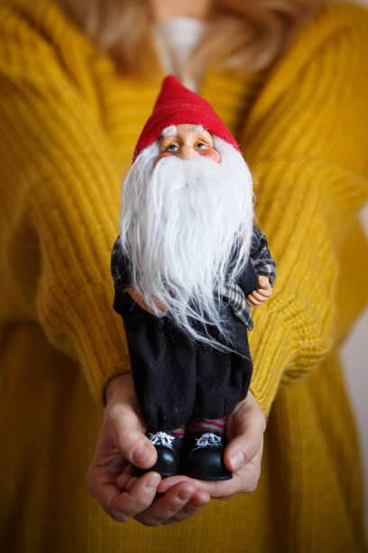 年轻女子抱着小圣诞老人。女孩手中拿着圣诞玩具。庆祝季节和圣诞节的概念图片下载