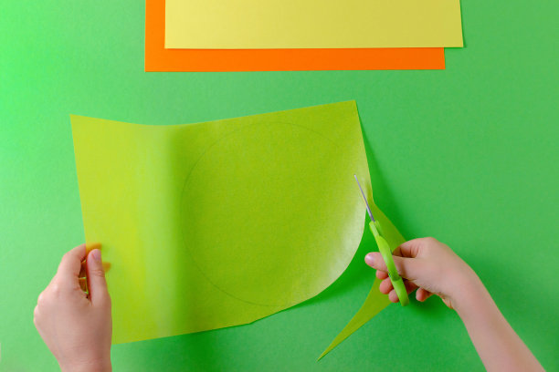 孩子的手用剪刀在透明纸上剪圈，俯视图，绿色图片下载