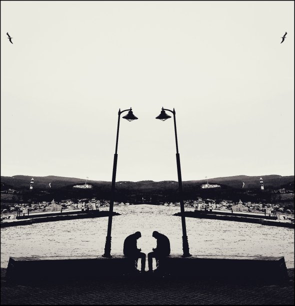 街灯和海岸线上坐着的人的单色多重曝光图片下载