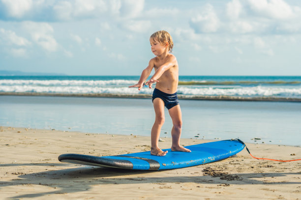 小男孩在热带海滩冲浪。在海浪上冲浪的孩子。孩子们积极的水上运动。和冲浪的孩子一起游泳。儿童冲浪课图片下载