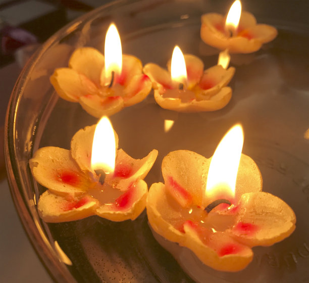 燃烧的蜡烛以花朵的形式漂浮在水面上。图片下载
