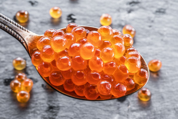 灰色石墨背景下的红色鱼子酱银勺。图片下载