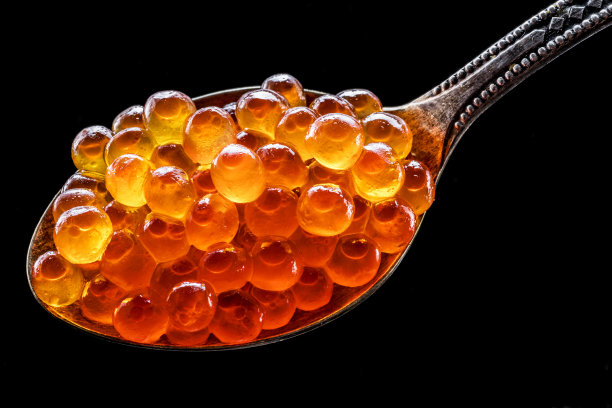 灰色石墨背景下的红色鱼子酱银勺。图片下载