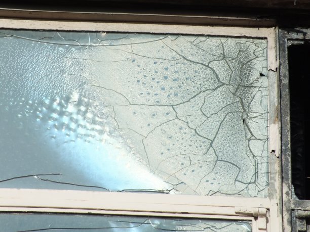 一所被火烧得部分熔化的被遗弃的房子的破碎的窗户和裂缝图片下载