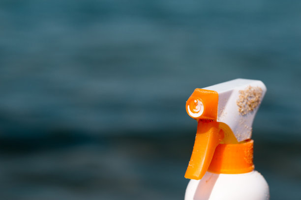 装有防晒霜的瓶子，模糊的背景是大海图片下载