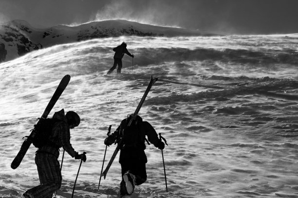 在多风的天气里攀登山坡的乡间滑雪者图片下载