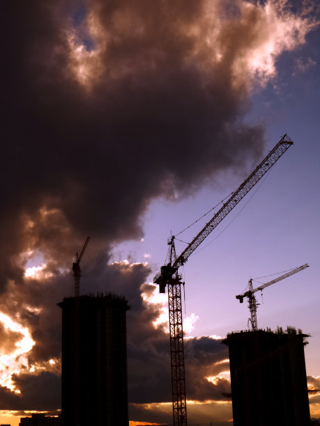 建筑起重机。住宅或公寓建筑。日落剪影照片。图片下载