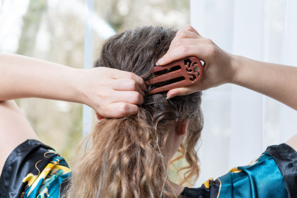 女性背部的特写，年轻的黑发女子用三叉木叉，中国，亚洲棍，发夹，站在家里，房子，公寓房间靠窗光，白色窗帘图片下载