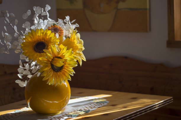 水平图像与细节的一个黄色花瓶与向日葵花在桌子上，光线从窗户进来图片下载