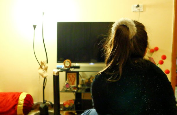 一个小女孩坐在床上看电视图片下载