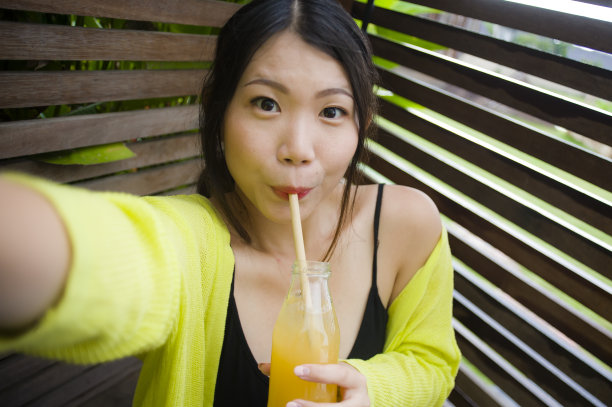 生活方式肖像年轻美丽和快乐的亚洲中国学生女孩拍照自拍照片户外喝橙汁微笑愉快享受假期旅行在甜蜜的脸表情图片下载