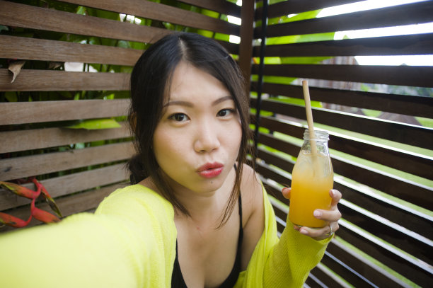 生活方式肖像年轻美丽和快乐的亚洲中国学生女孩拍照自拍照片户外喝橙汁微笑愉快享受假期旅行在甜蜜的脸表情图片下载
