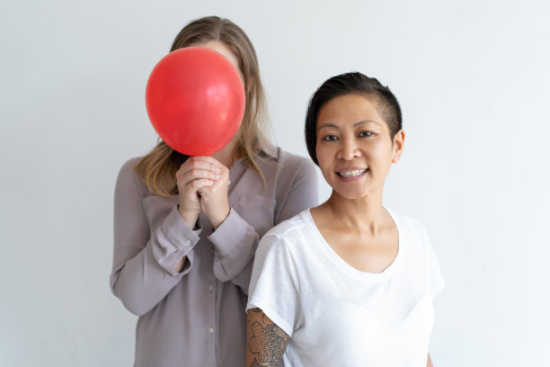 两个乐观的女人在镜头前摆姿势，拿着红色气球图片下载