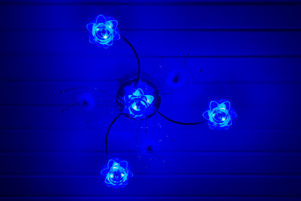 现代的花灯悬挂在天花板上，现代的家庭内部背景，在黑暗中闪烁着蓝色的光图片下载