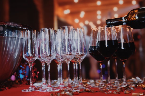 在一个新年派对上，服务员把红酒倒进玻璃杯里图片下载