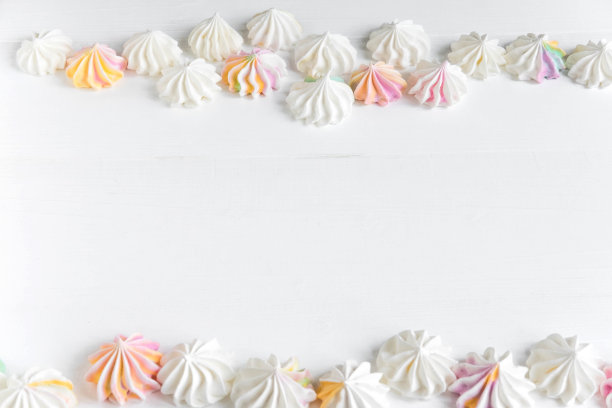 带有颜色蛋白糖霜的文本框架。背景与糖果横幅。白色木质背景上的五颜六色的蛋白糖霜。糖果横幅，咖啡厅，糖果店的基础。酥皮的横幅图片下载