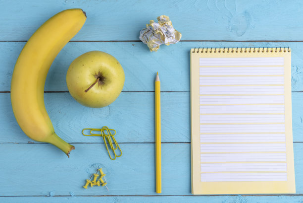 新鲜的水果和办公用品放在一张蓝色的桌子上，平躺的形象图片下载
