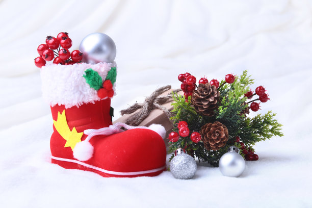 红色圣诞老人的靴子和圣诞礼物在雪的背景。节日快乐组成。图片下载