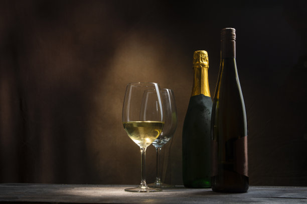 漆黑的夜里，木桌上放着两瓶酒和两杯酒。图片下载