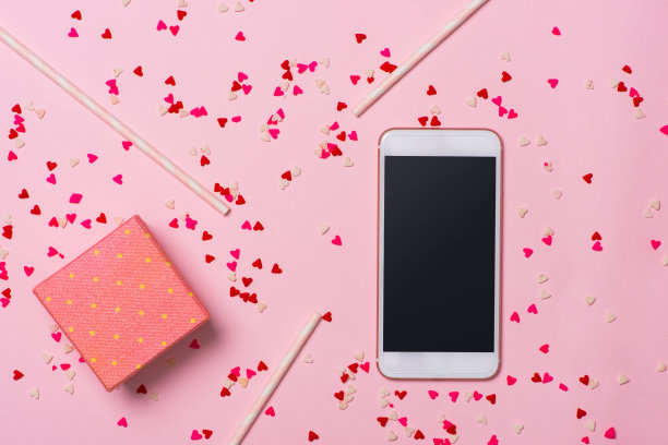 情人节，手机在粉红色的背景与红色的心和盒子与礼物，他们之间的爱和连接，浪漫的图片，适合广告图片下载