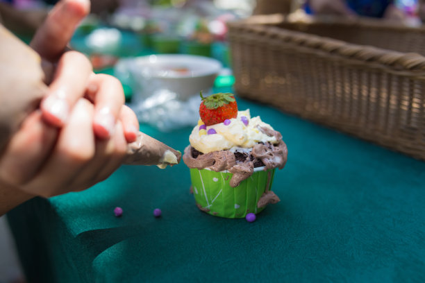 有趣的孩子用草莓、巧克力、糖和香草装饰纸杯蛋糕图片下载