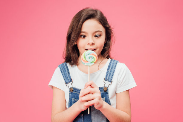 滑稽的孩子拿着棒棒糖孤立在粉红色上图片下载