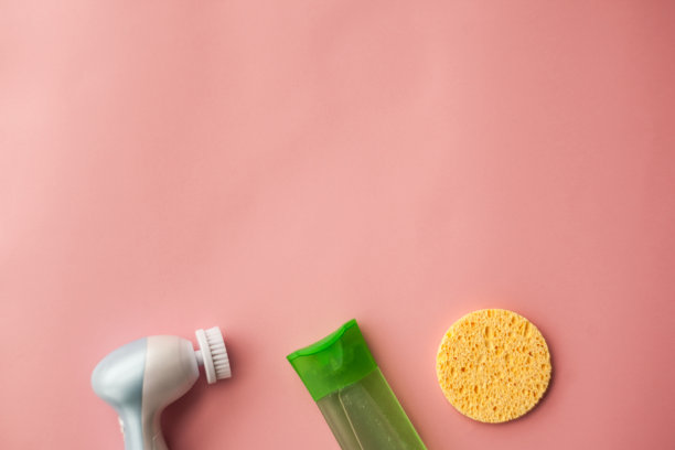 用电刷洁面乳和洁面啫喱，在粉色背景上使用海绵。面部护理。美容设备。深皮肤清洁。有选择性的重点图片下载