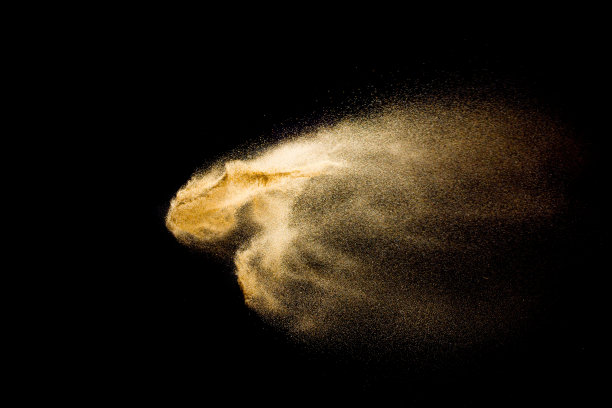 抽象的沙子云。金色的沙子在黑暗的背景下飞溅。图片下载