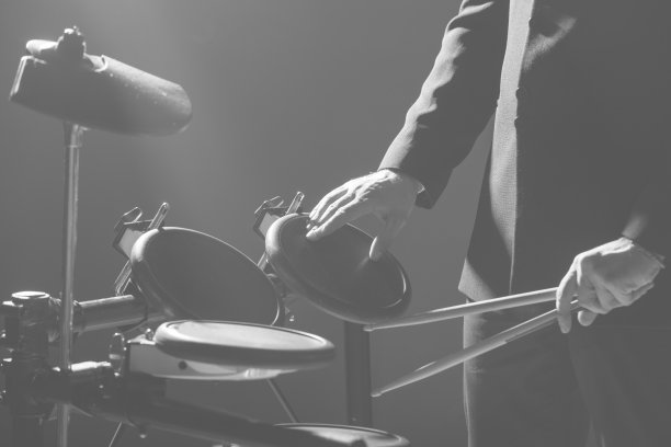 鼓手。这家伙拿着鼓槌在电子鼓的背景下。拿着鼓槌的年轻人。图片下载