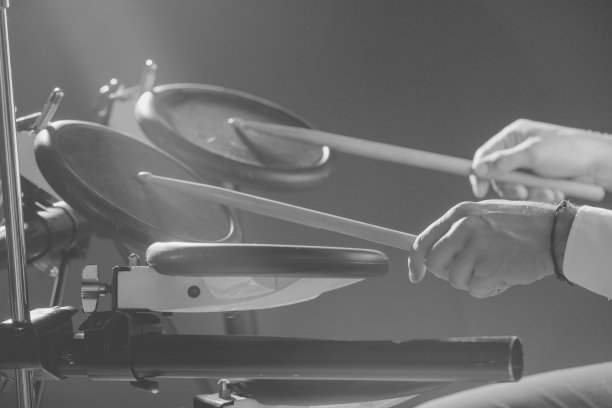 鼓手。这家伙拿着鼓槌在电子鼓的背景下。拿着鼓槌的年轻人。图片下载