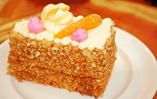 白色盘子里放着一块杏仁蛋糕和橙色水果图片下载