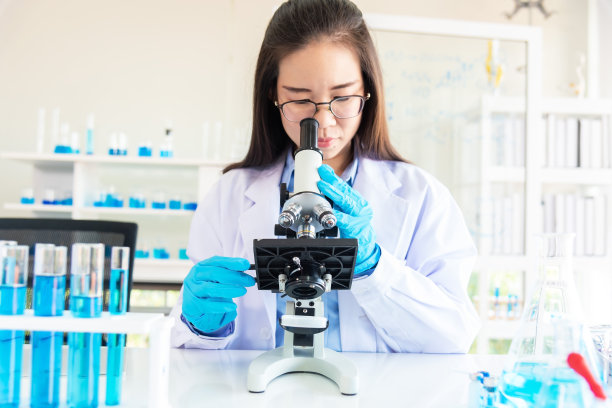有魅力的科学家在实验室里透过显微镜看东西图片下载