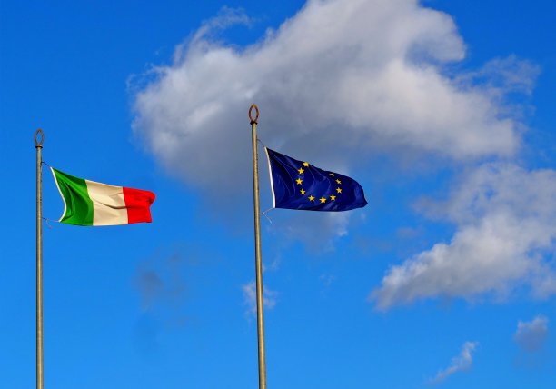 意大利国旗和欧盟的旗帜，映衬着蓝天和蓬松的云朵图片下载
