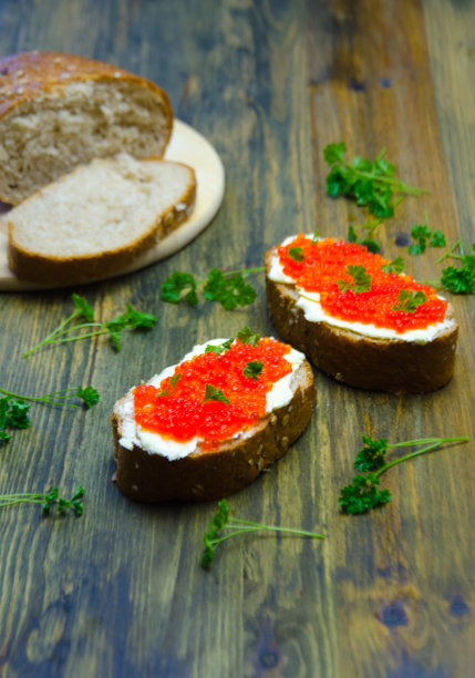 三明治与红色鱼子酱和一些绿色在木背景选择图片下载