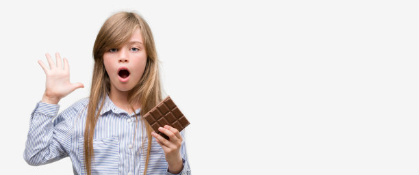 年轻的金发小孩拿着巧克力棒非常高兴和兴奋，胜利者的表情庆祝胜利尖叫着大大的微笑和举起手图片下载