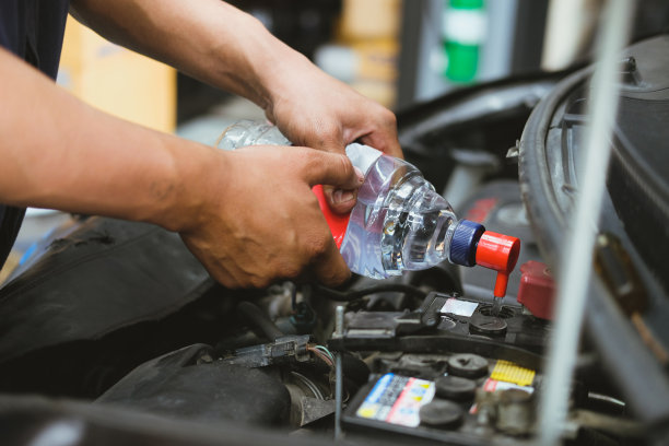 在汽车维修服务中，机械师将蒸馏水注入汽车蓄电池图片下载