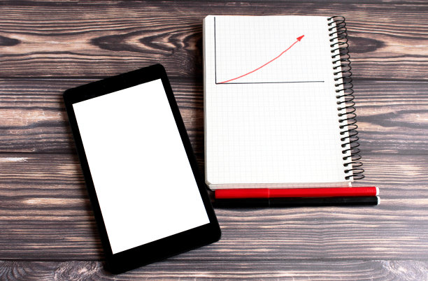 一个白色屏幕的笔记本电脑上的文字，和一个记事本的书写躺在一个黑暗的背景。图片下载